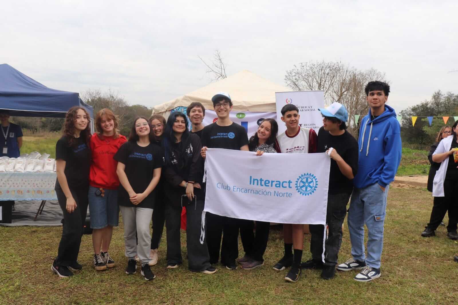 Miembros del Interact Club Encarnación Norte sonriendo juntos durante un evento comunitario.